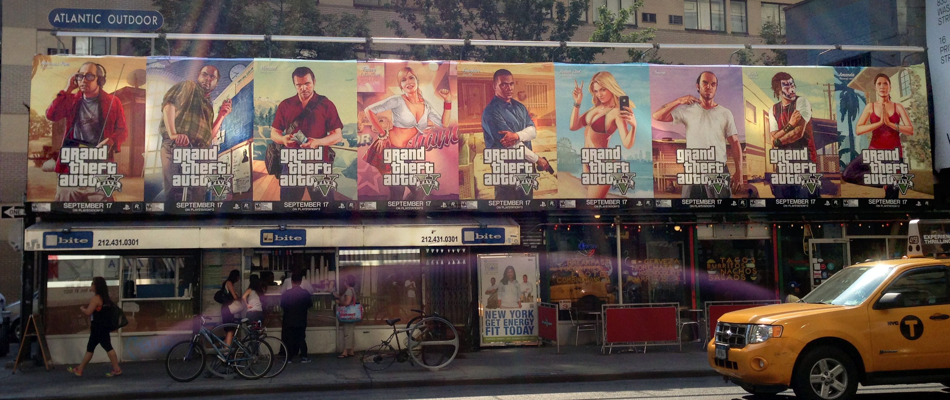 A row of seven Grand Theft Auto V character posters, each dated September 17, mounted above a city storefront with a yellow taxi passing.
